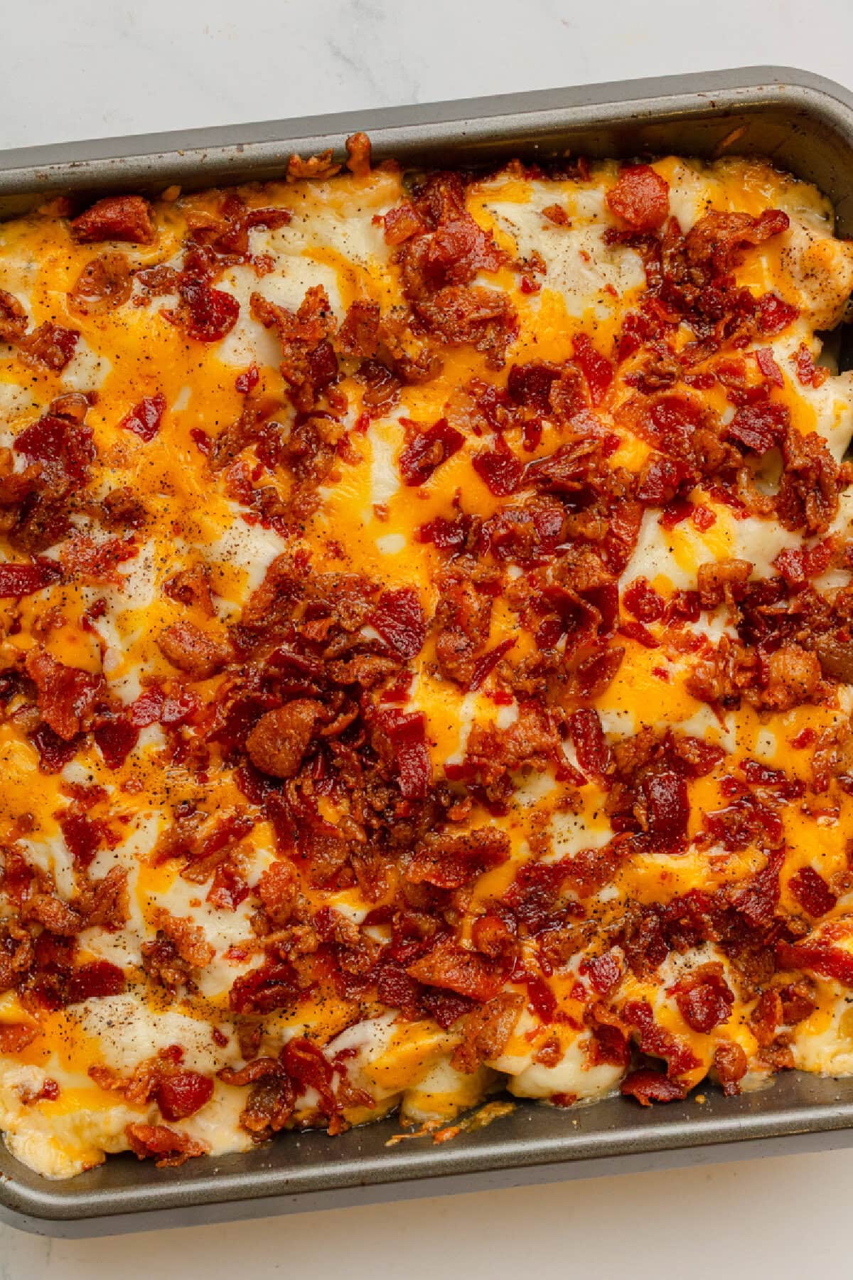 Crispy bacon on top of a cheesy chicken Ranch casserole.