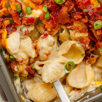 Creamy and cheesy chicken bacon Ranch casserole being served with a spoon from a baking pan.