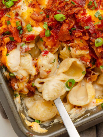 Creamy and cheesy chicken bacon Ranch casserole being served with a spoon from a baking pan.