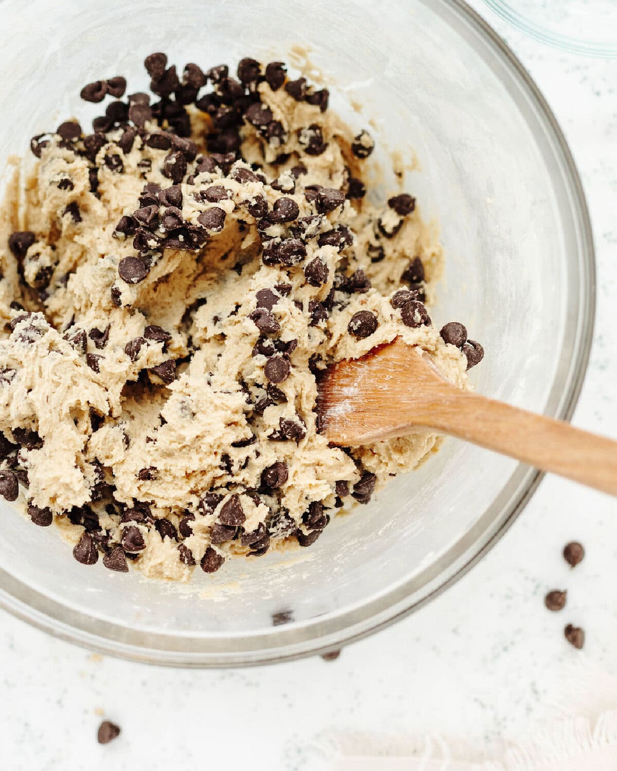 Chocolate chips folded into cookie dough in a mixing bowl.