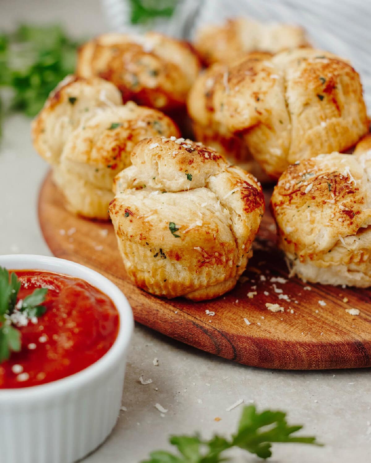 Mini garlic monkey bread baked and served on a wood serving board with dipping sauce.