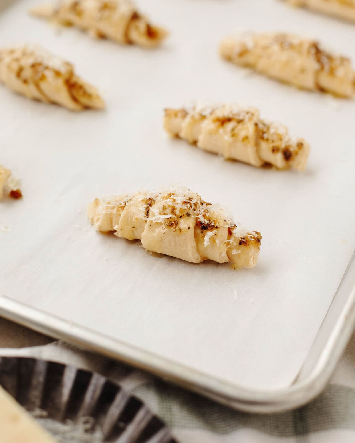 Crescent rolls brushed with garlic, melted butter, and Oregano on a parchment lined cookie sheet.