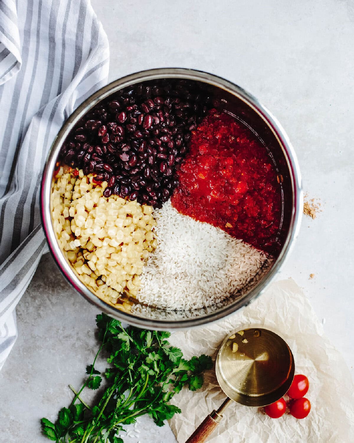 Black beans, corn, rice, and salsa placed on top of chicken breasts, broth, and taco seasoning in an instant pot.
