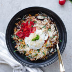 Chicken taco bowls served in a black bowl with sour cream, cheese, tomatoes, and cilantro.