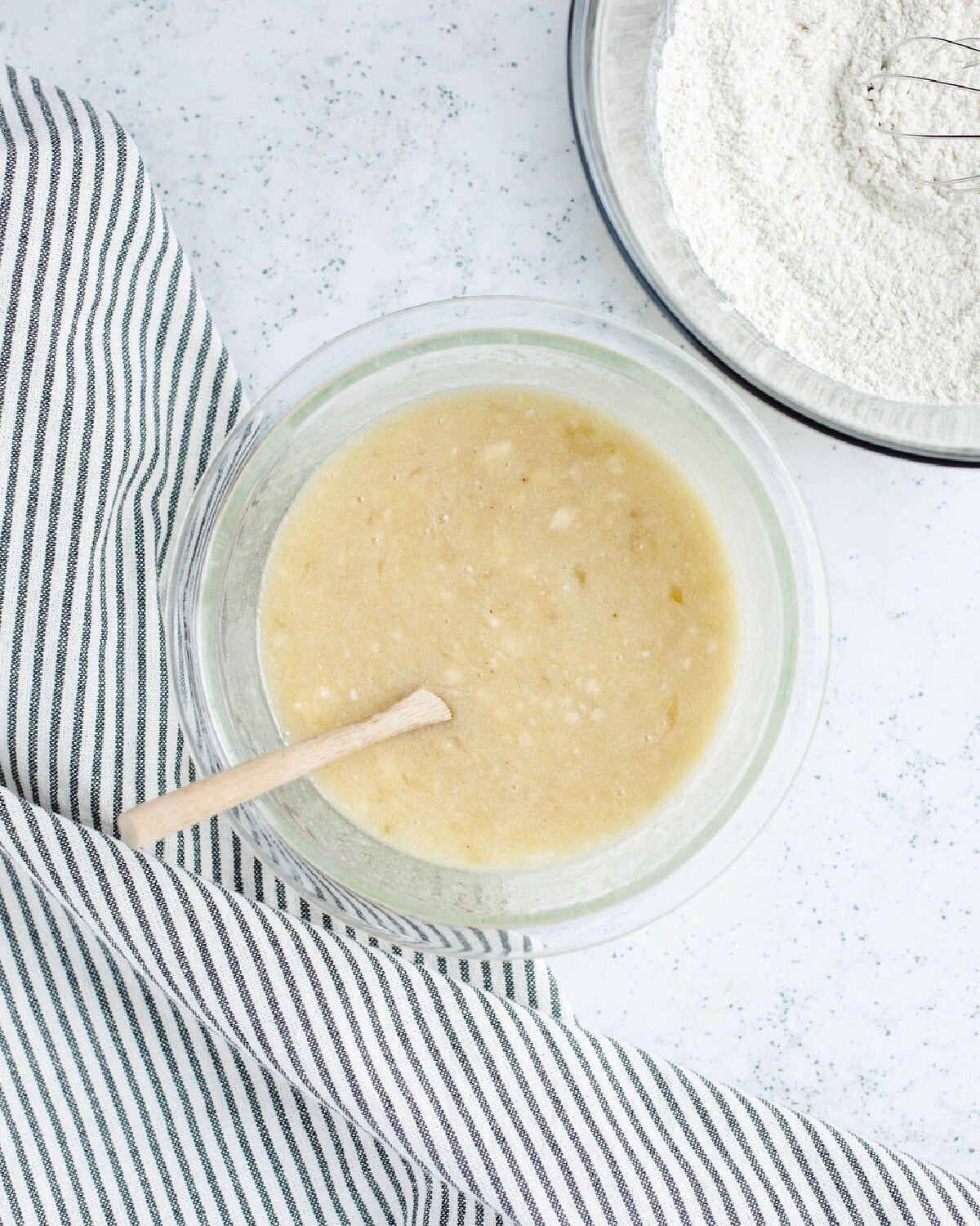Bananas, sugar, egg, and melted butter combined in a mixing bowl.