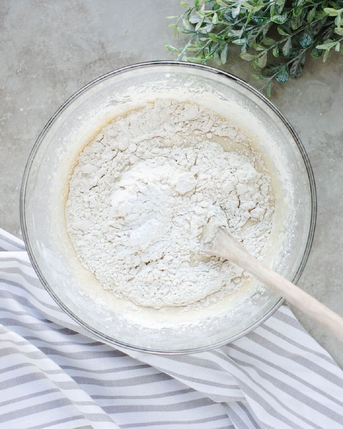 Dry ingredients folded into wet ingredients to form a cake batter in a glass bowl.