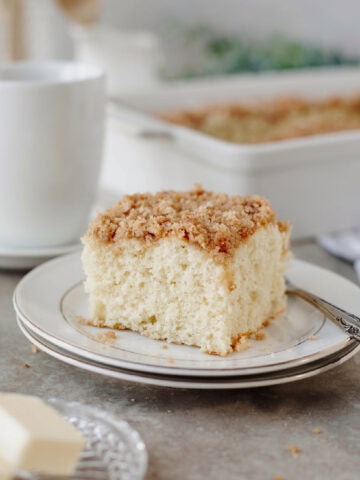 A slice of morning cake with a streusel topping on a small white plate.