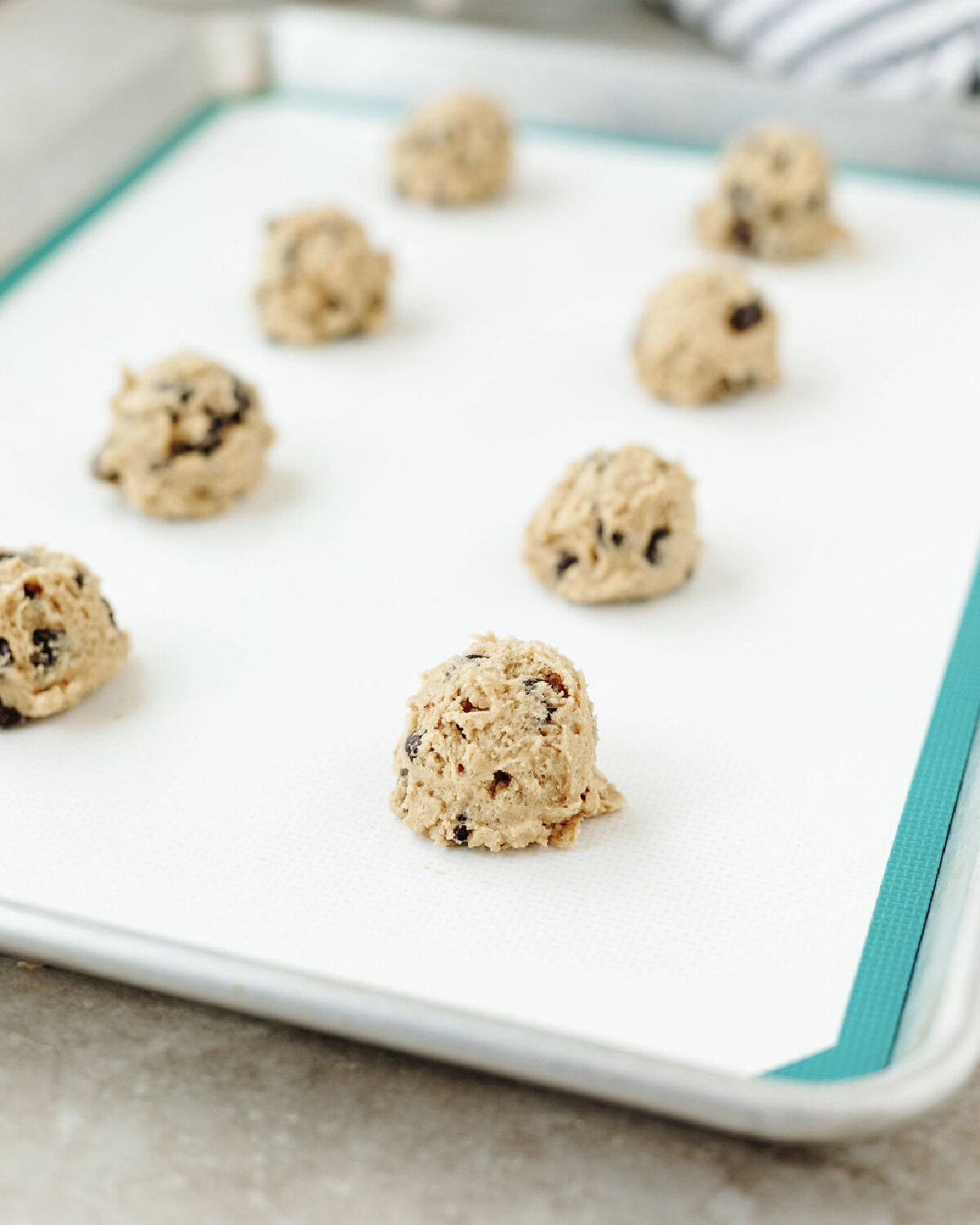 Scooped cookie dough on a silicone lined baking mat.