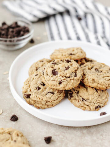 A white plate with a stack of peanut butter oatmeal chocolate chip cookies ready to serve.