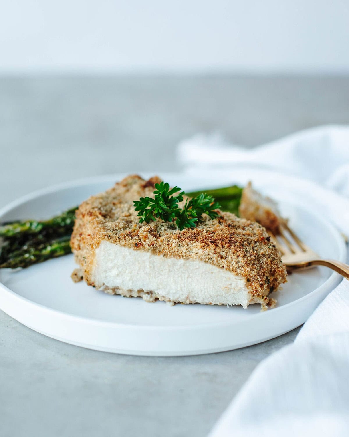 Sliced Ranch breaded pork chop showing cooked center on a white plate.