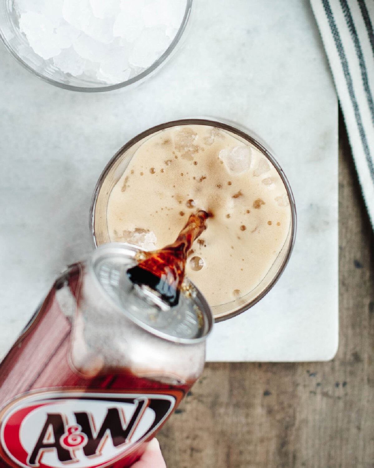 Pouring root beer into a glass with ice.