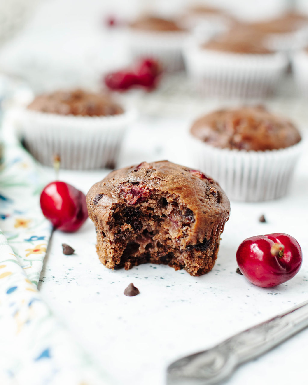 A bite taken out of a chocolate cherry muffin to show the fluffy texture on the inside.