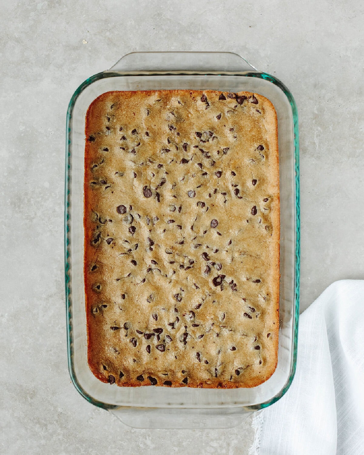 A chocolate chip cookie base baked in a glass 9x13 baking dish.