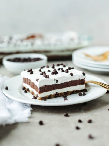A sliced piece of chocolate chip pudding cake on a white plate with a gold fork.