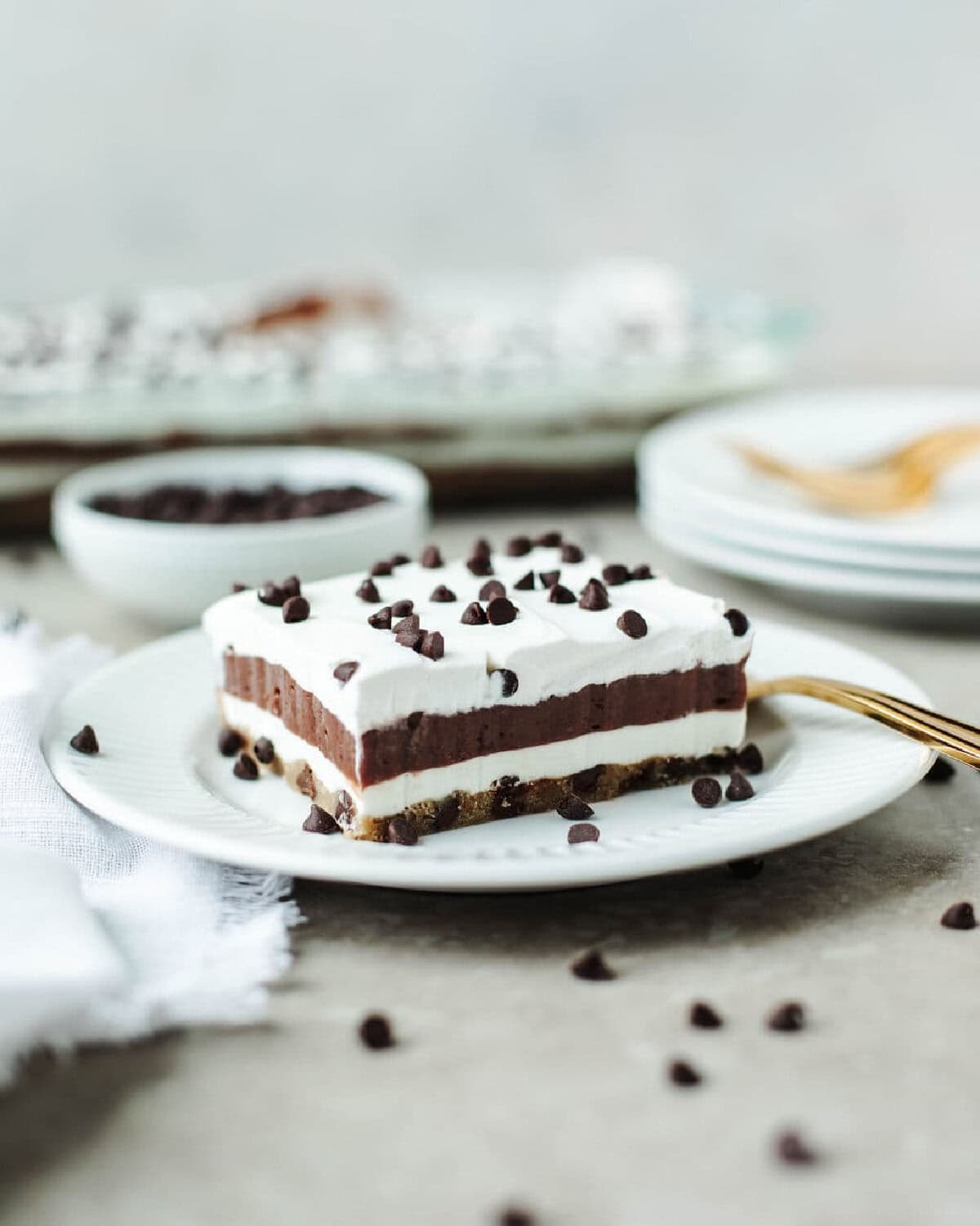 A sliced piece of chocolate chip pudding cake on a white plate with a gold fork.