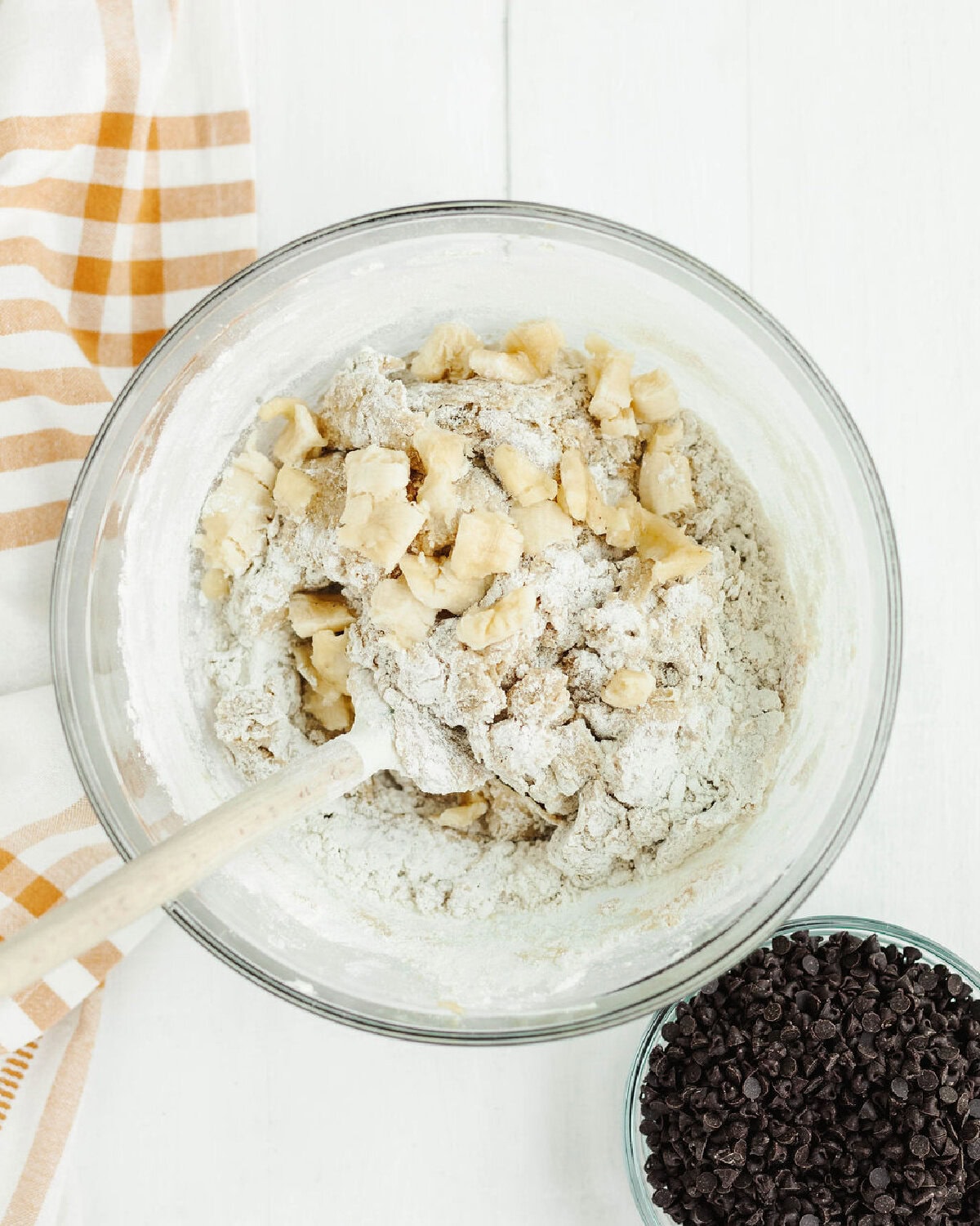 Flour and chopped banana added into brownie batter in a mixing bowl.