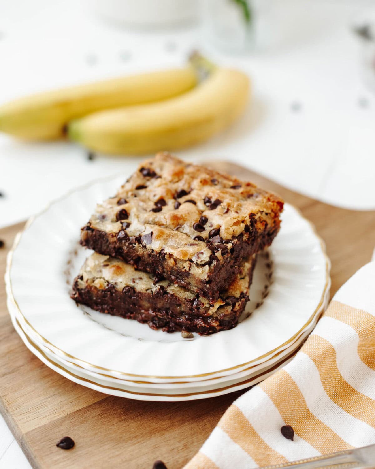 Stacked chunky monkey banana brownies on a white plate.