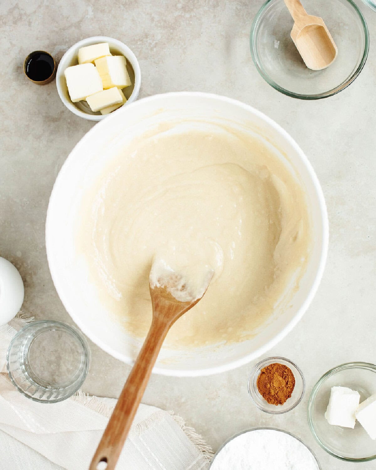 Egg, milk, and oil added to the dry ingredients in a mixing bowl using a wood spoon.