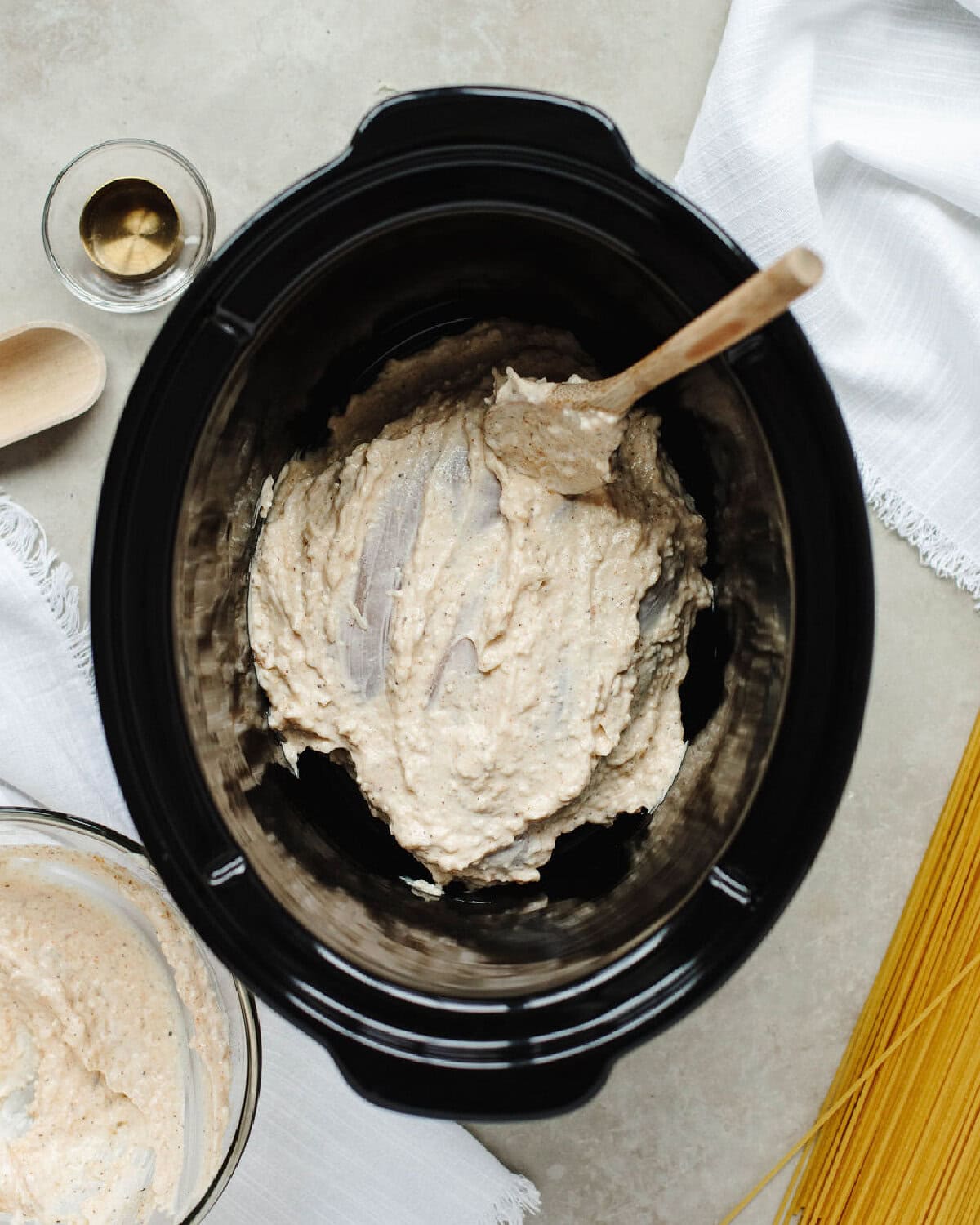 A creamy mayonnaise sauce spread on top of chicken breasts in a crock pot.