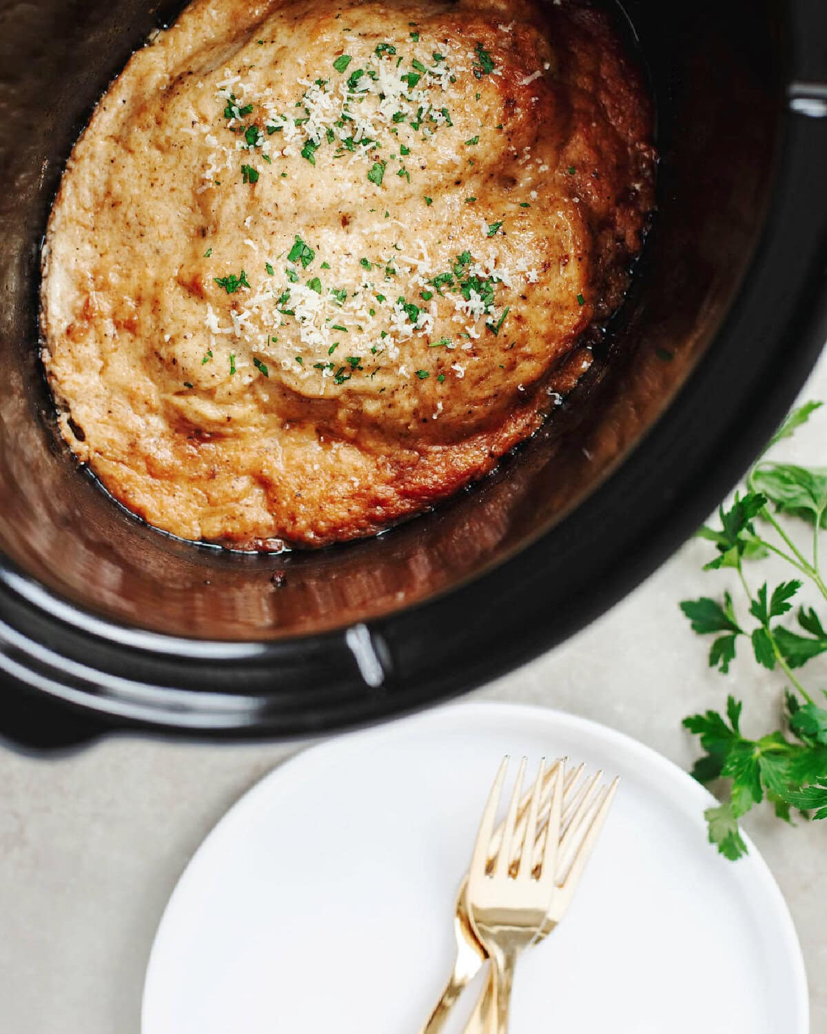 Tender chicken breasts in a slow cooker topped with a mayonnaise sauce and ready to serve.