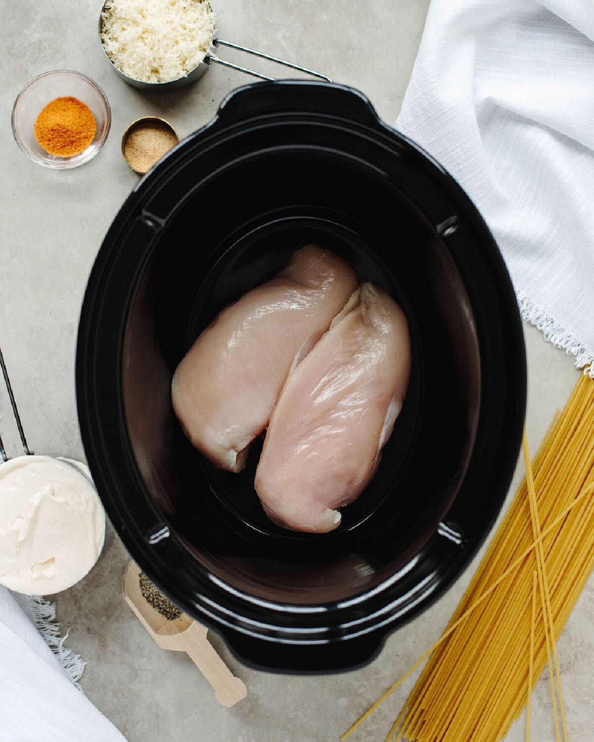 Raw chicken breasts placed on the bottom of a slow cooker liner.