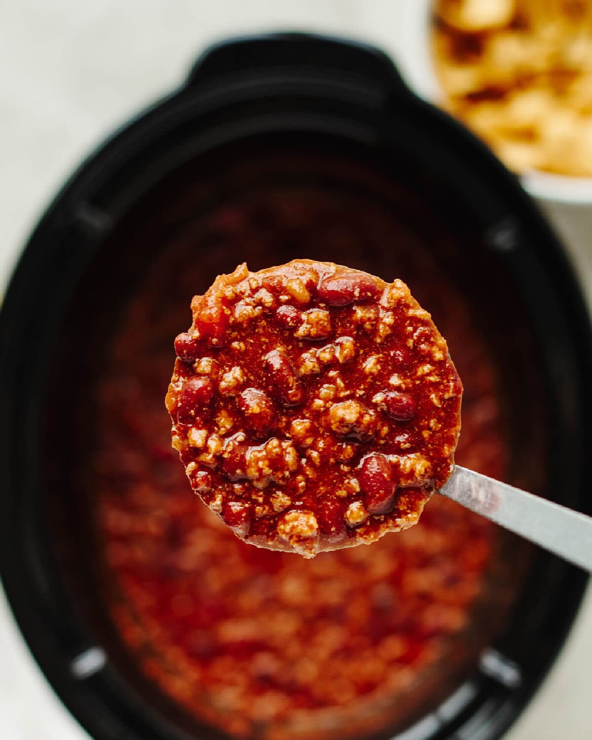 A spoon with homemade chili ready to scoop and serve.