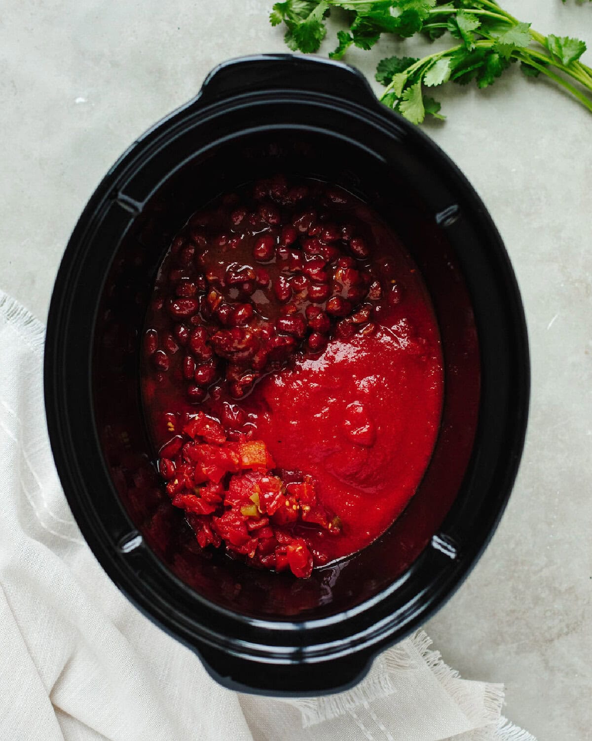 Rotel, tomato sauce, and chili beans combined in a slow cooker liner.