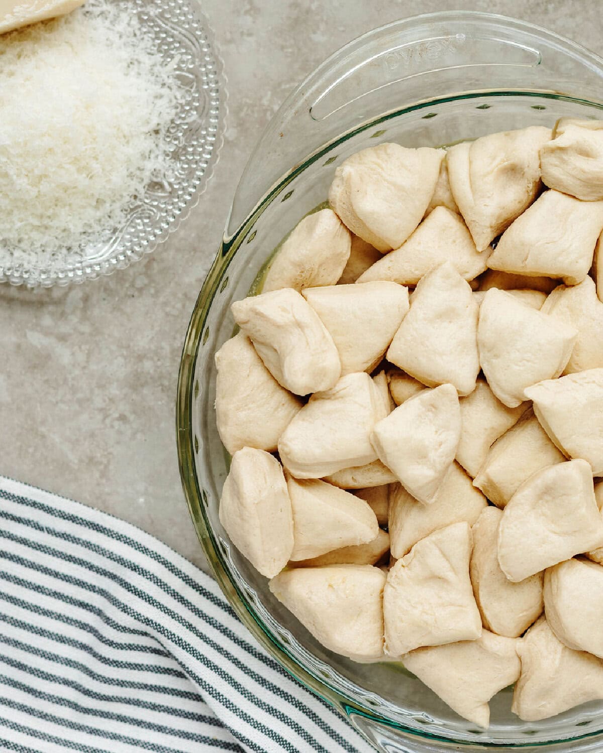 Quartered biscuit pieces layered in a glass pie dish.