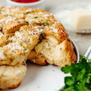 An up close look at garlic pull apart bread on a white plate with a side of marinara sauce.