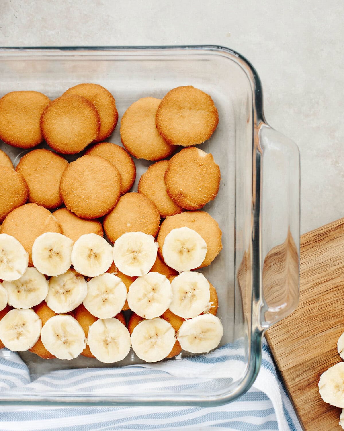 Vanilla wafers and banana slices lined in a glass pan.