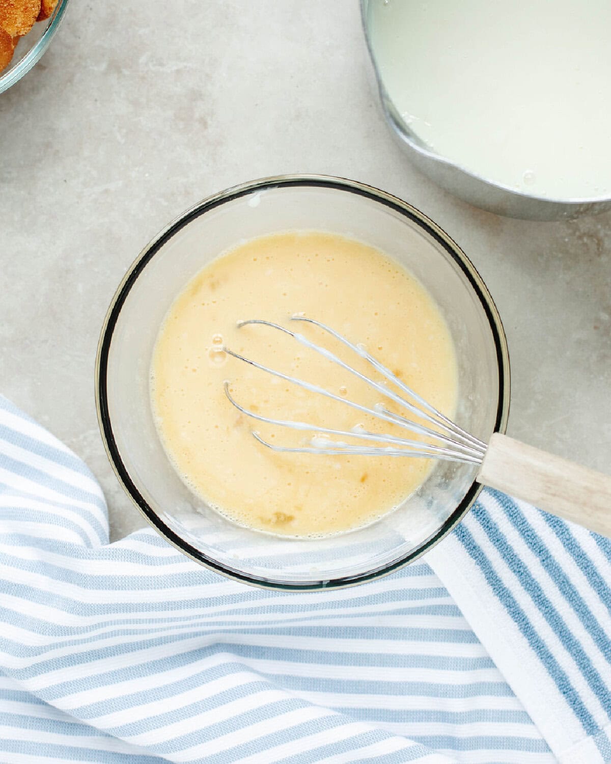 Eggs and hot egg mixture combined in a glass bowl.