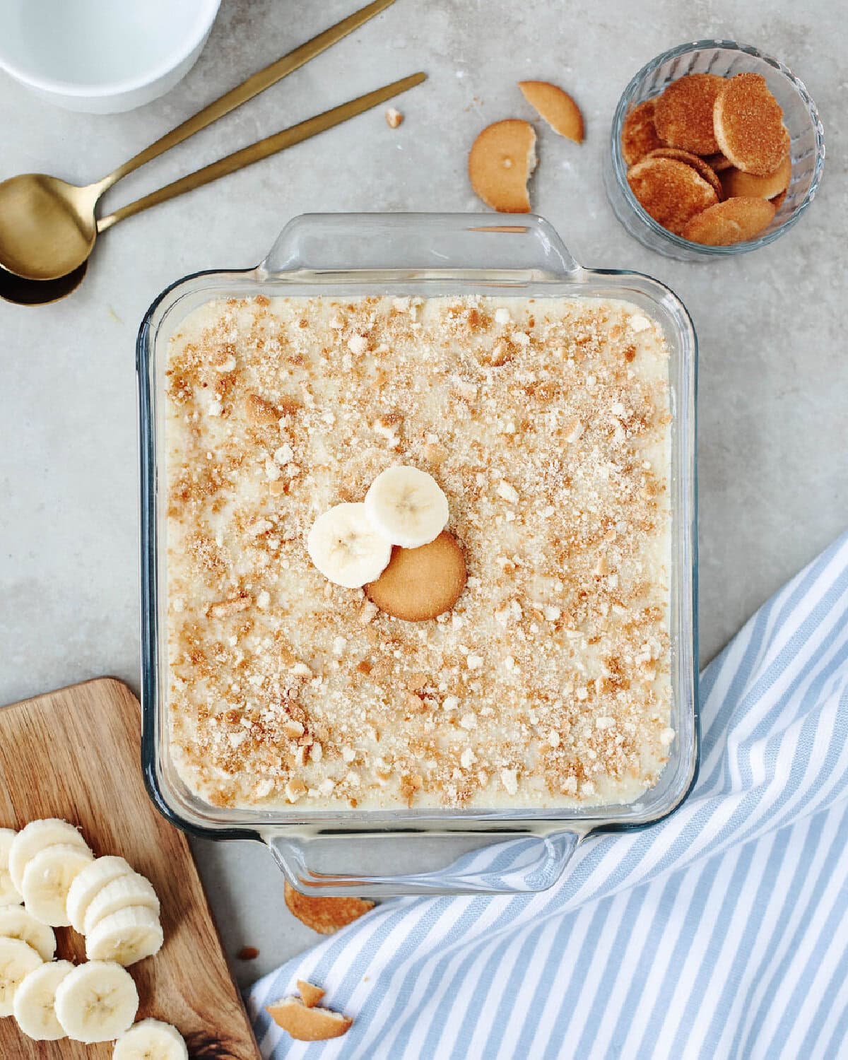 Banana pudding made in an 8x8 glass pan and crushed vanilla wafers spread on top.