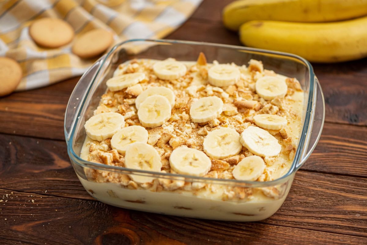 An 8x8 baking dish of vanilla pudding and fresh bananas ready to serve.
