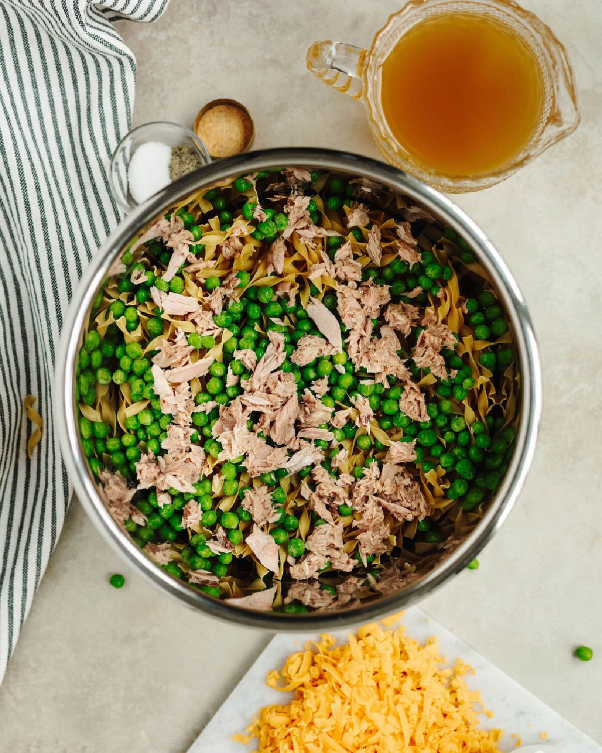 Canned tuna and peas added on top of uncooked egg noodle in an Instant Pot liner.