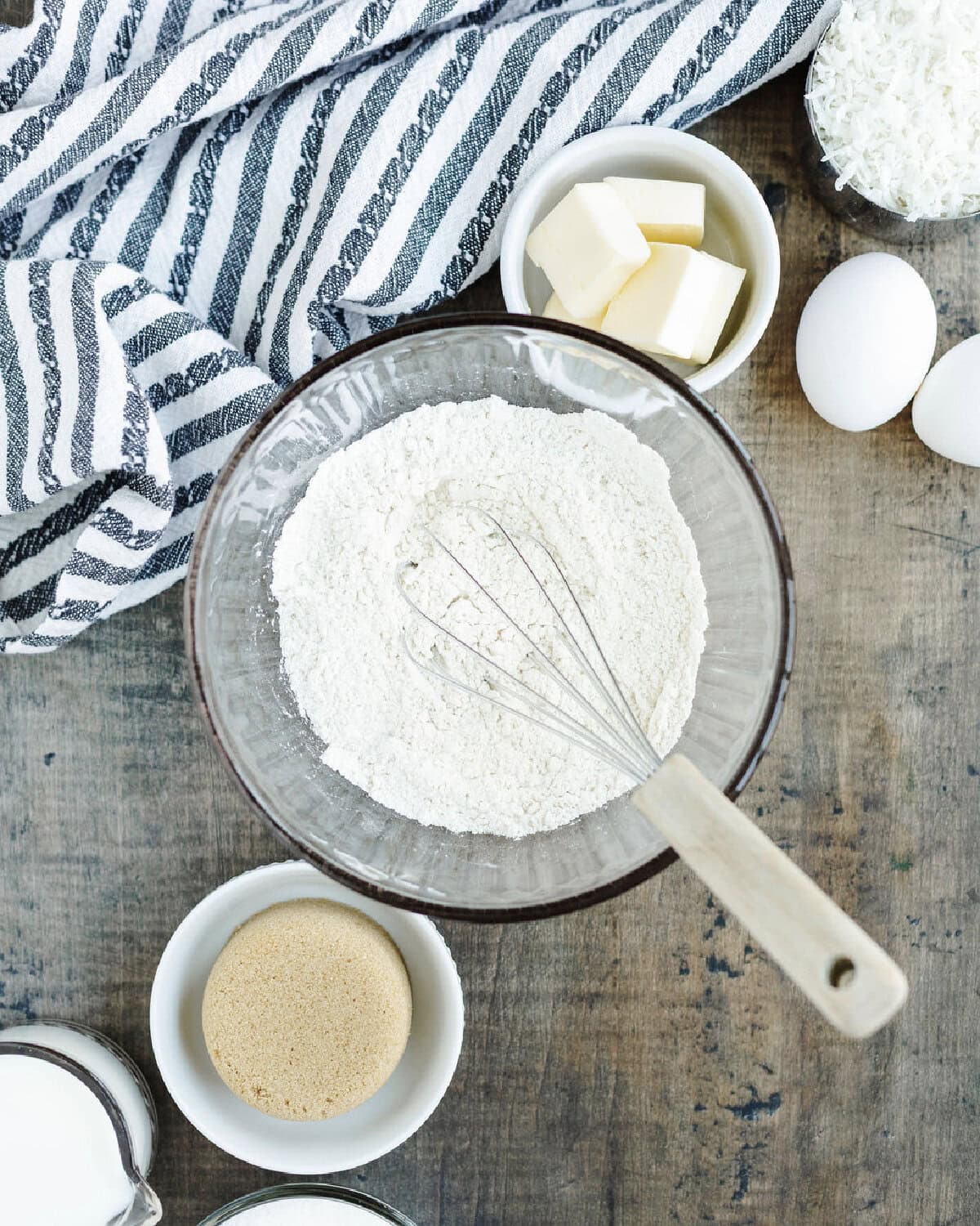 Flour, baking powder, and salt combined in a glass bowl using a whisk.