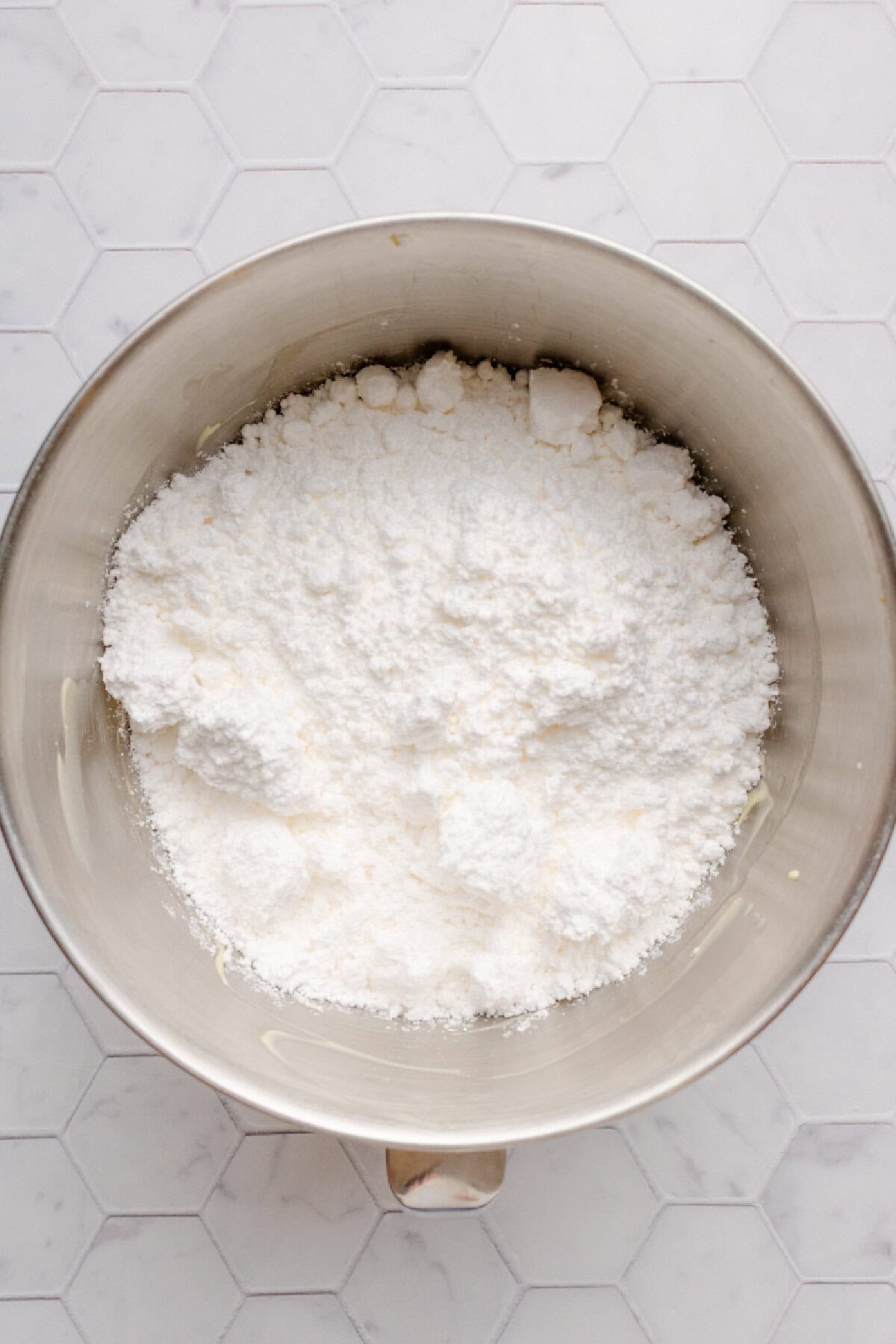 Powdered sugar add to a cream cheese mixture in a mixing bowl.