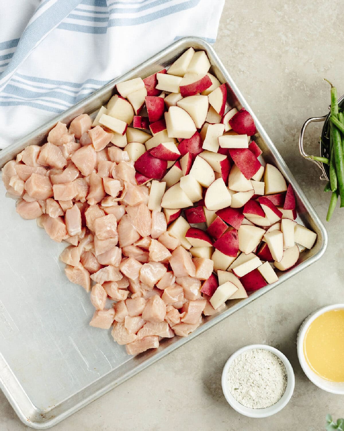 Diced potatoes and chicken lined on a baking sheet.