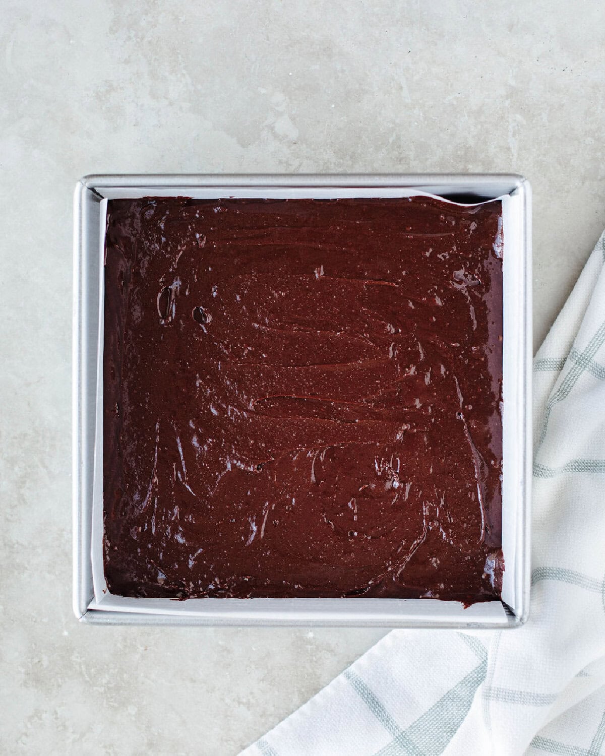 Brownie batter spread evenly into a prepared 8x8 baking pan.