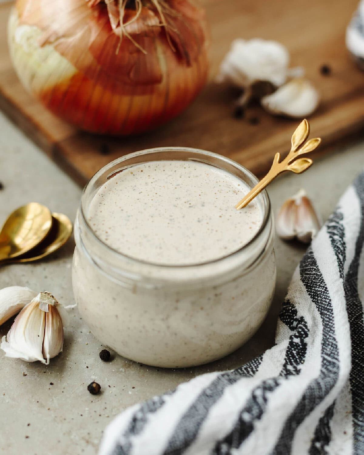 A white tangy BBQ sauce in a small glass jar with a spoon.