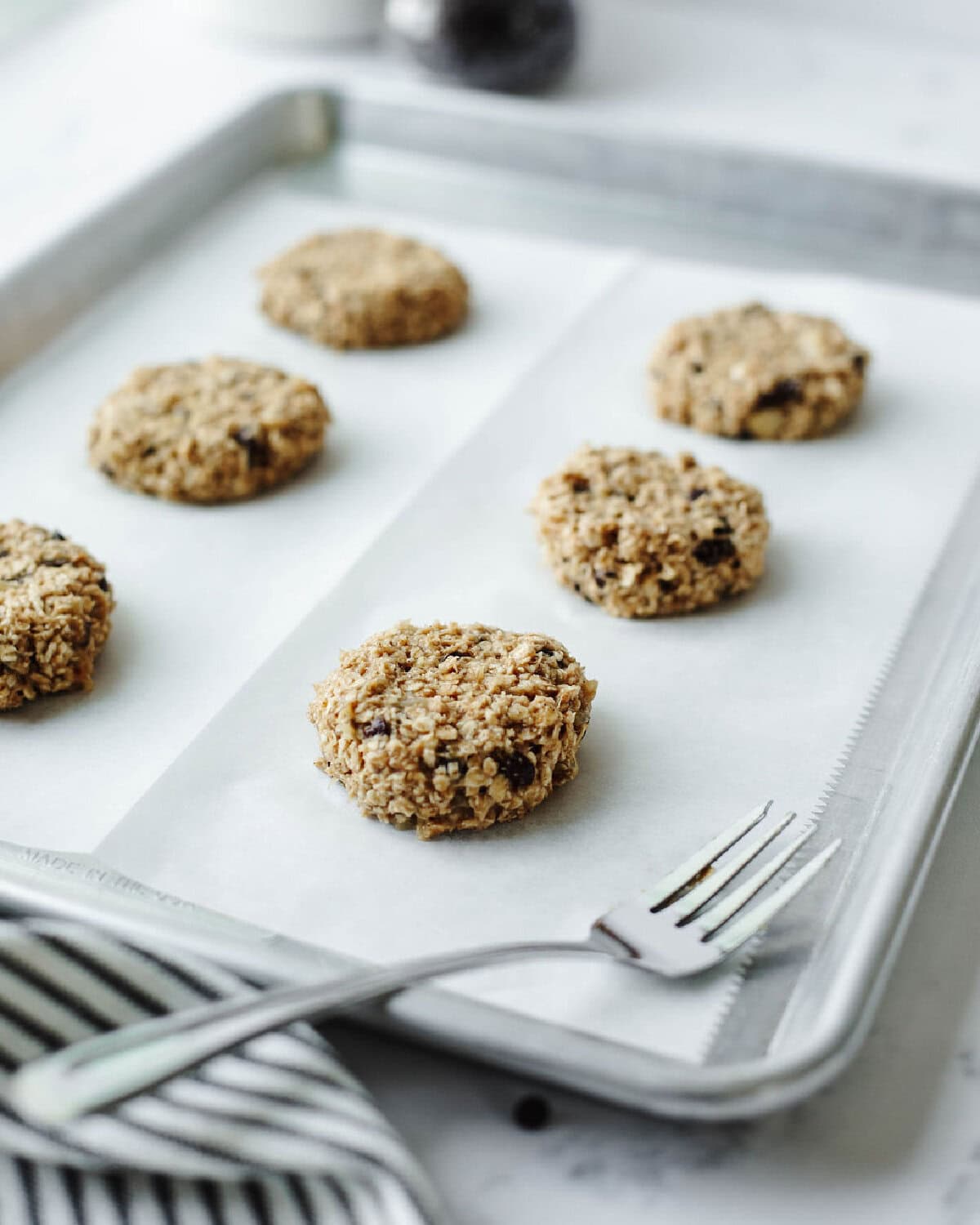 Cookie dough on a baking sheet flattened using a fork before going into the oven.