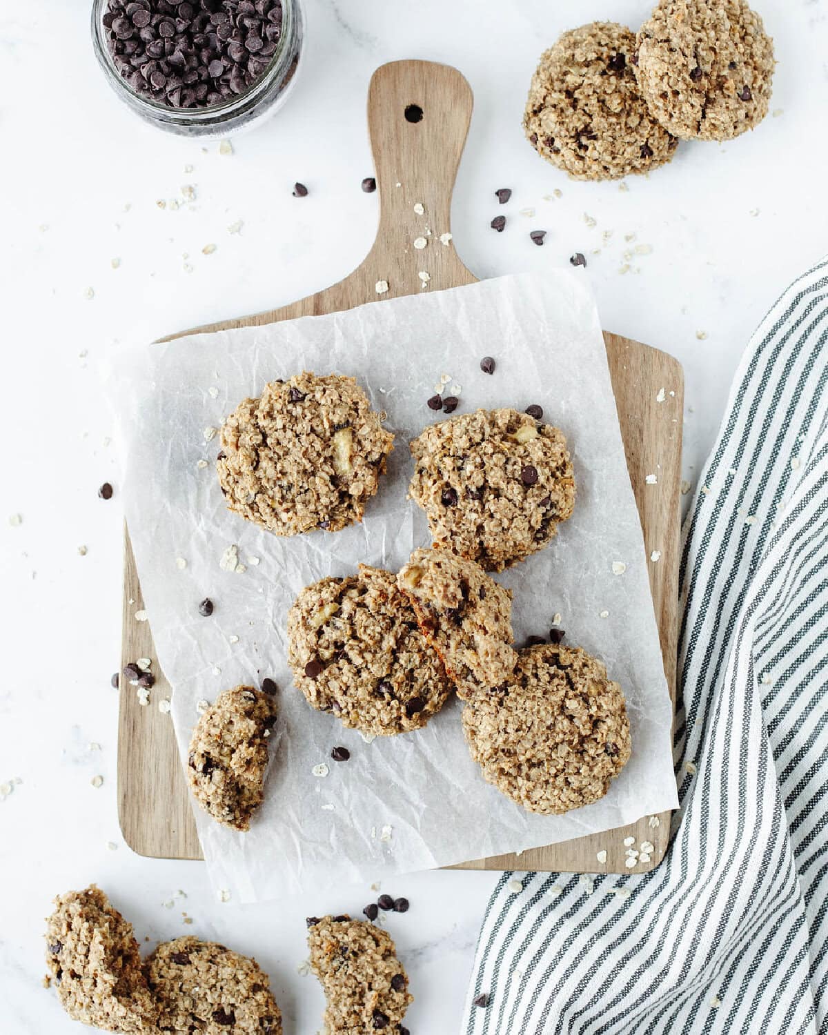 A wood serving platter with parchment paper and several banana oatmeal peanut butter cookies on top ready to enjoy.