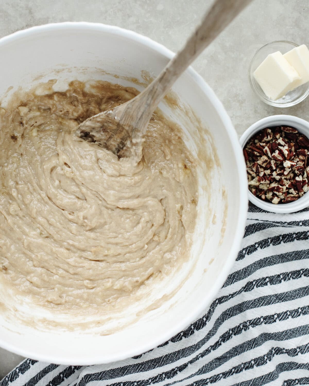 Dry ingredients and wet ingredients combined in a mixing bowl with a wood spoon to create a muffin batter.