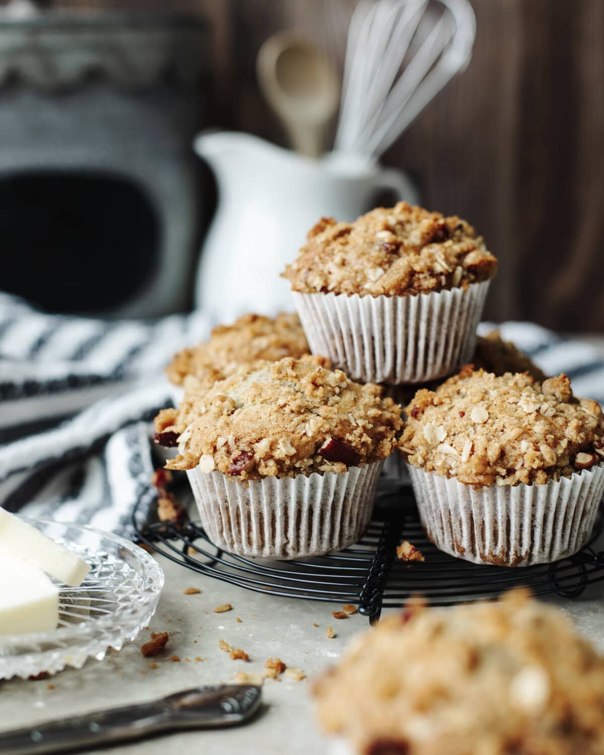 Stacked banana pecan muffins with paper liners on a wire serving tray.