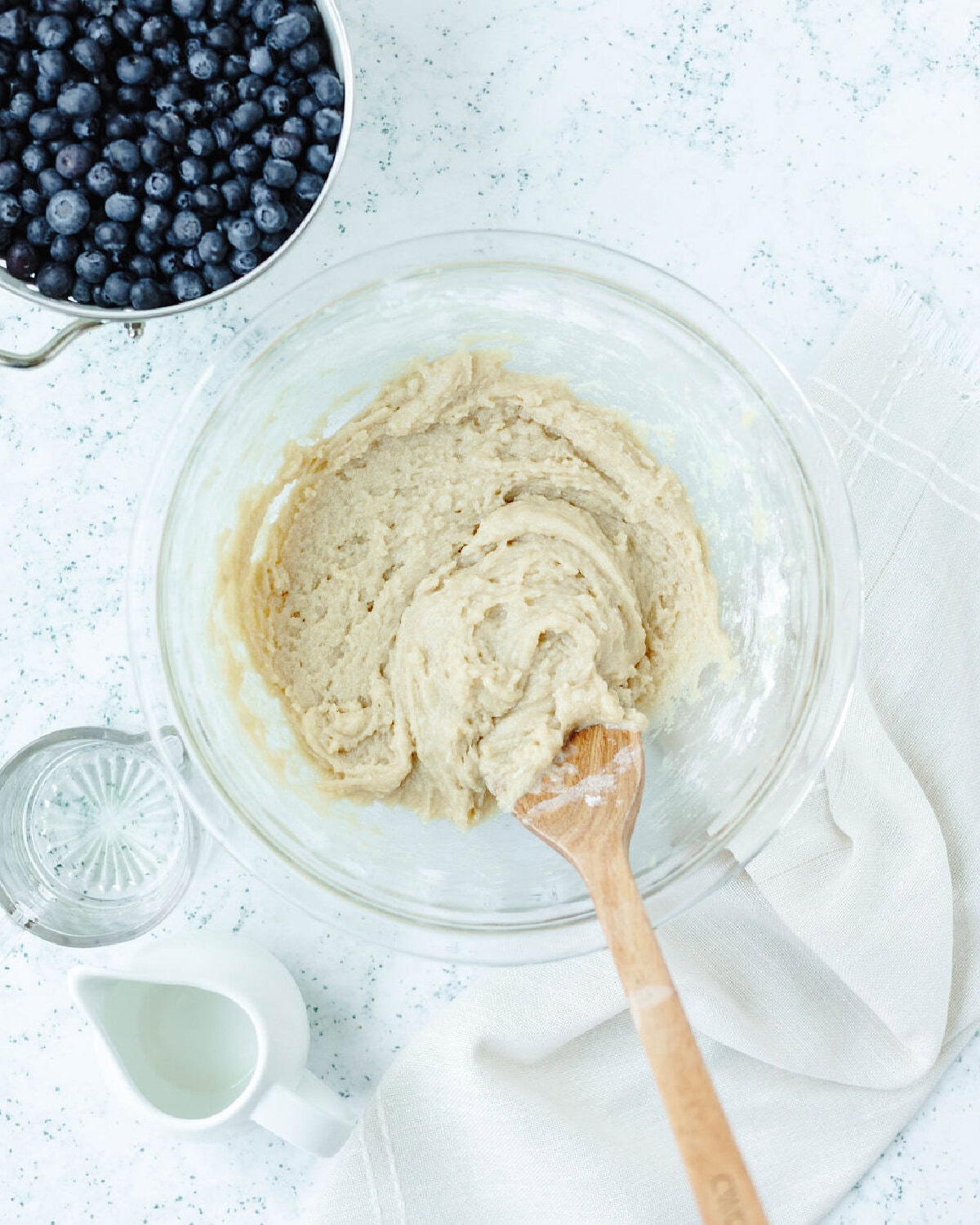 Muffin batter combined with a wood spoon in a glass mixing bowl.