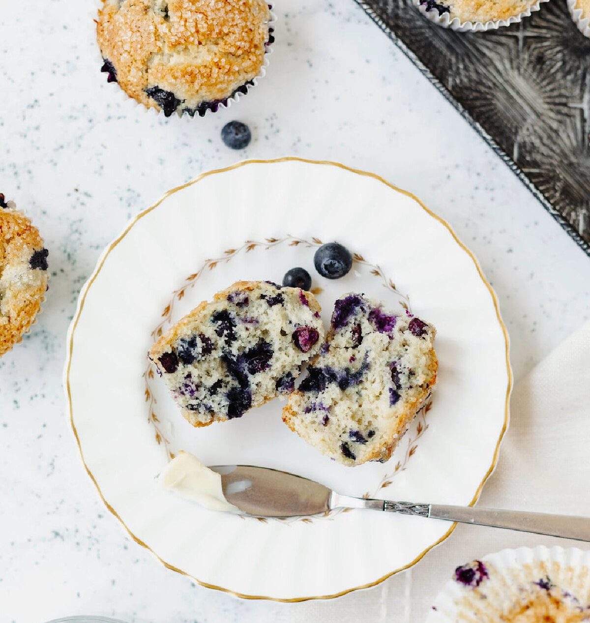 A sliced blueberry muffin on a small plate to show the inside fluffy texture and juicy berries throughout.