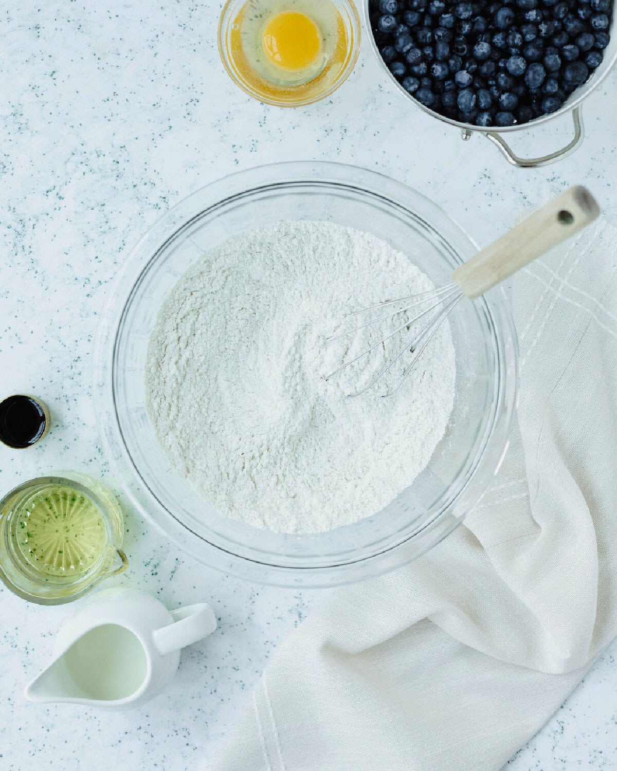 Flour, sugar, baking powder, and salt whisked together in a glass mixing bowl.