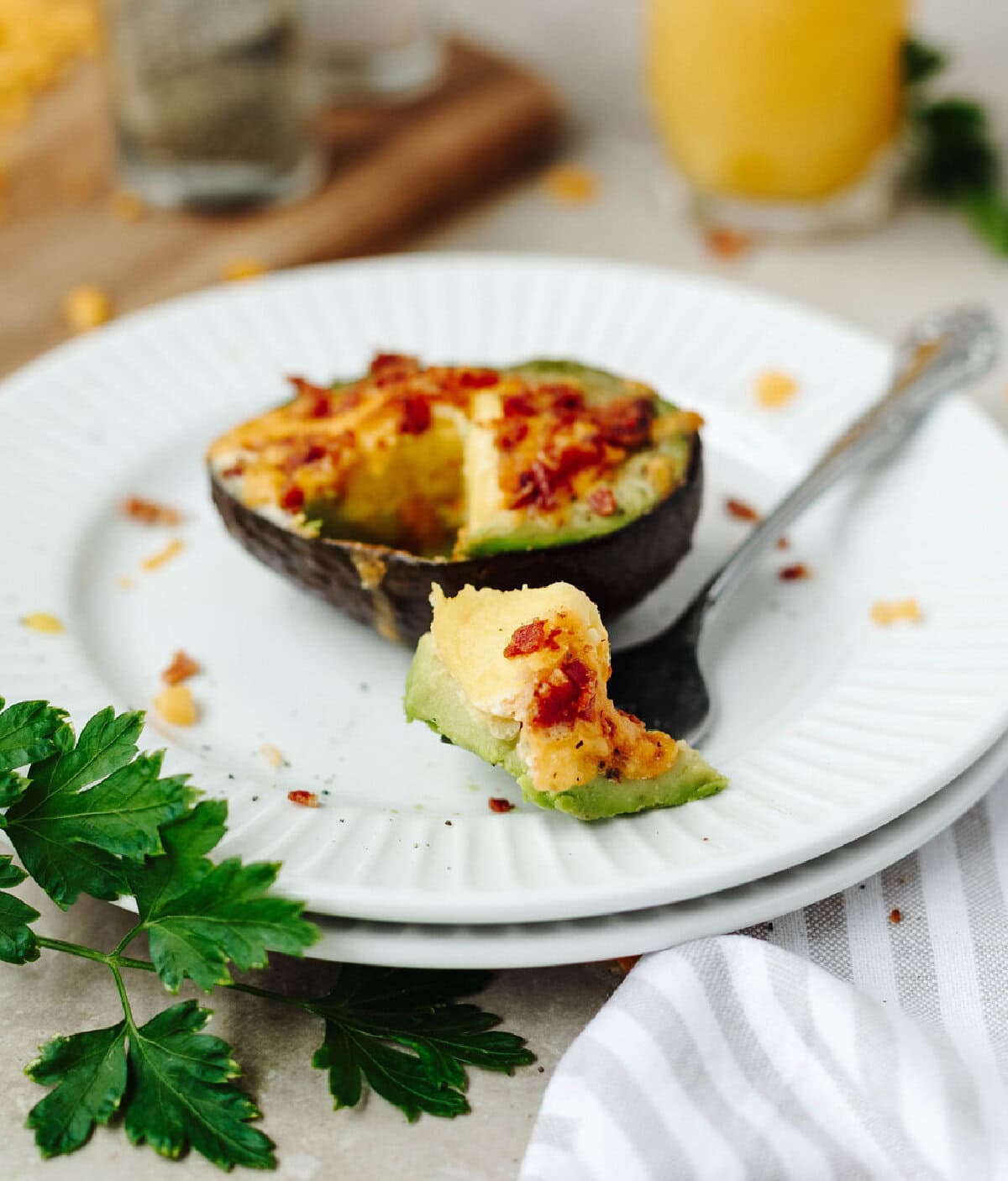 A fork taking a bite of a breakfast stuffed avocado on a white plate.