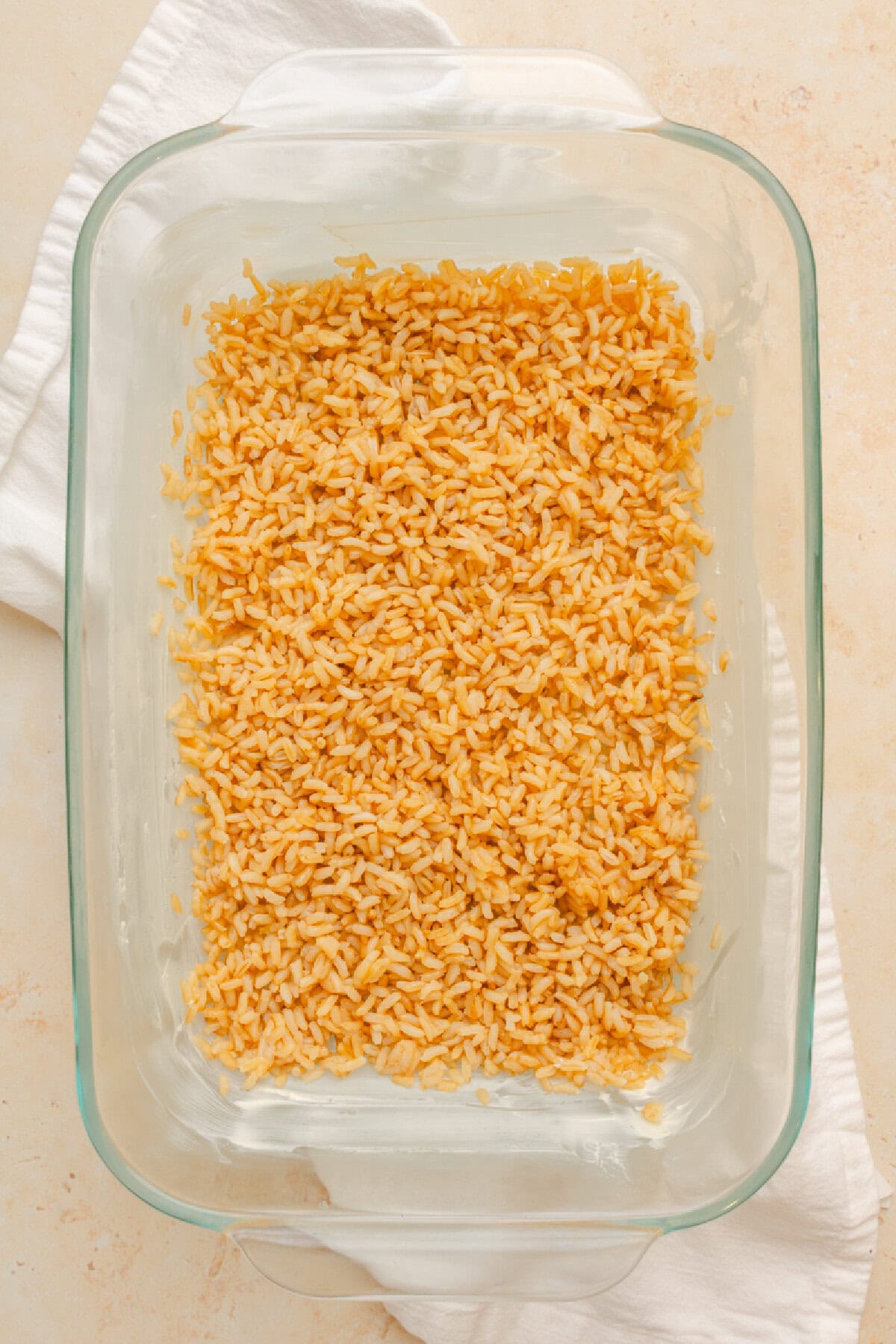 Brown rice spread in an even layer in a 7x11 baking dish.