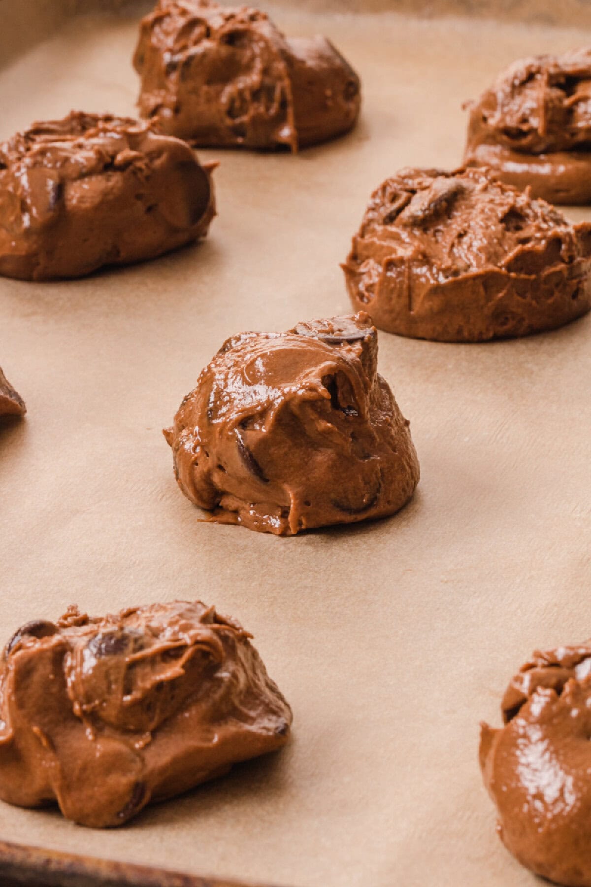 Cookie dough batter scooped onto a parchment lined baking tray.