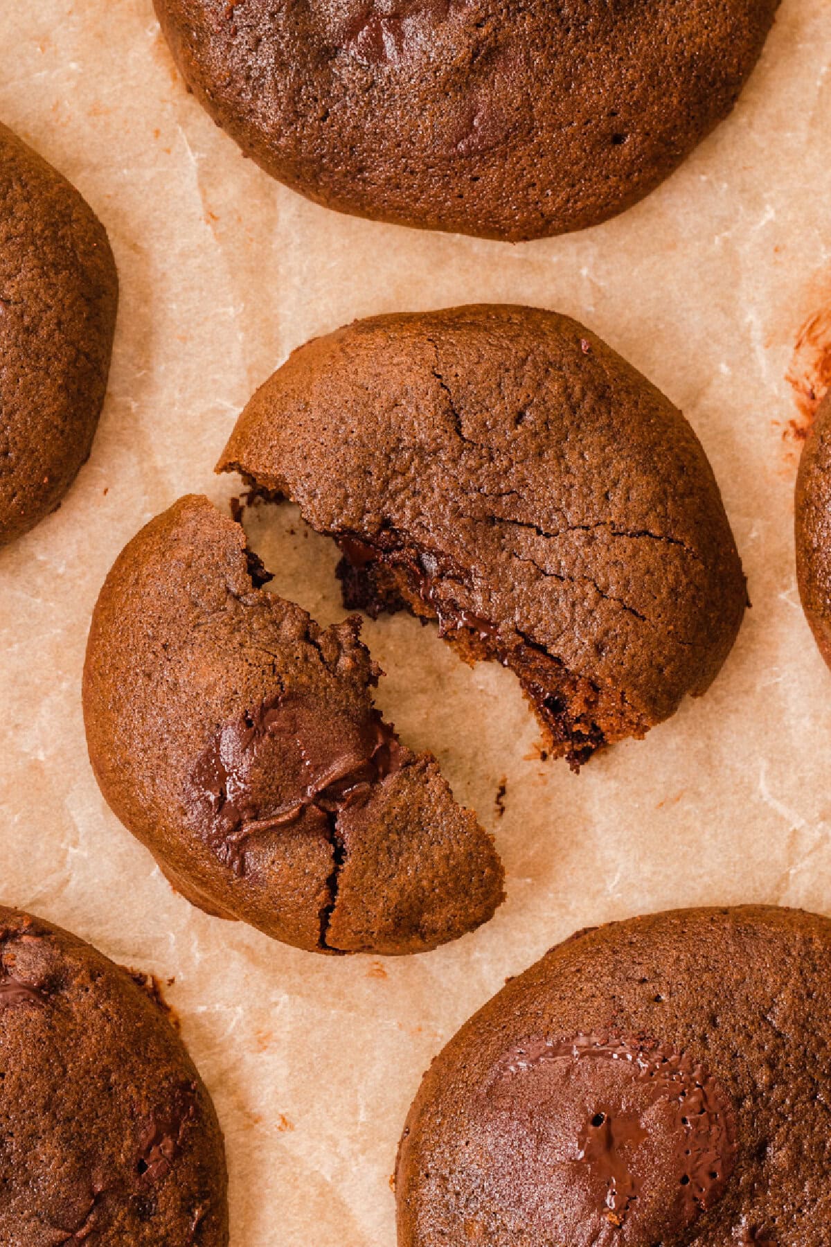 A chocolate brownie cookie broken in half to show ooey gooey center.